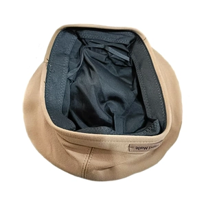 Detail of wool beret featuring black inner lining, adjustable drawstring, and handmade tag