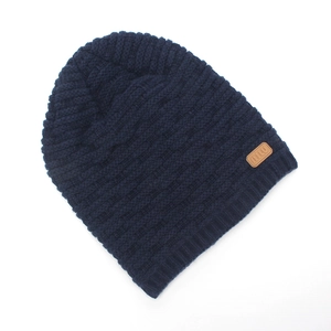 Close-up of navy blue ribbed knit beanie with leather logo patch for winter