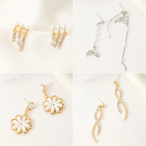 Four styles of gold earrings featuring pearls, rhinestones, and floral charms displayed on silk