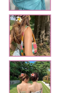 Detail of realistic white plumeria flower hair claw clip with colorful crochet bag