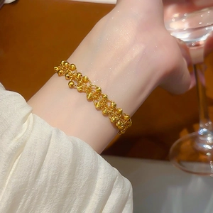 Close-up of 24K gold-plated beaded bangle with a luxurious woven metal texture on wrist