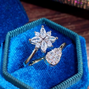 Dettaglio macro dell'anello in argento con fiori e gocce su velluto blu