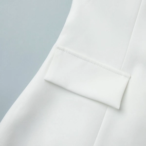 Detailed close-up of a white lace blazer featuring a flap pocket and textured fabric
