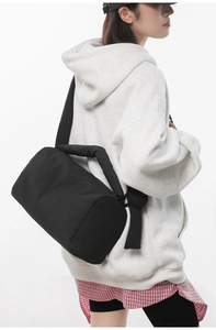 Close-up of a quilted black nylon shoulder bag with a wide padded strap for daily use