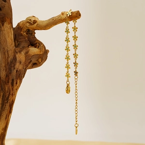 Golden titanium steel daisy bracelet with blue crystal centers on rustic wood branch