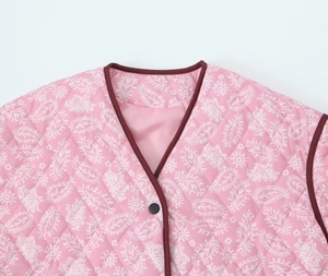 Detail of pink paisley quilted jacket with contrast binding and black round buttons