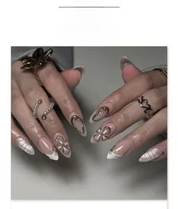 Detail of almond press-on nails with 3D metallic flowers, pearls and embossed textures