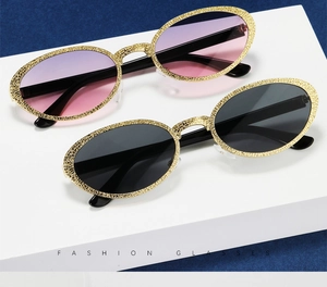 Close-up of vintage oval sunglasses with textured gold frames and tinted lenses