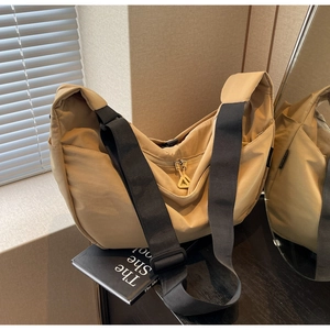 Close-up of khaki nylon crescent bag with adjustable wide strap and metal zipper