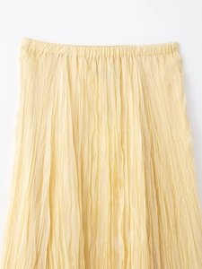 Detailed view of elastic waist and pleated fabric texture on yellow midi skirt
