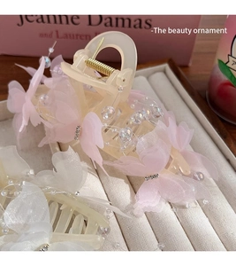 Detail of pink and white butterfly hair claws with beads and mesh on a jewelry tray
