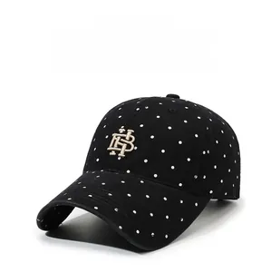 Close-up of golden HB embroidery and white polka dots on black cotton baseball cap