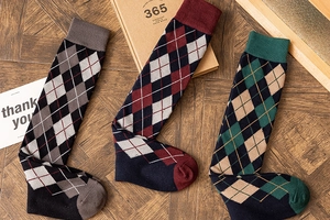 Close-up of argyle patterned knee-high socks in retro colors on a rustic wooden background