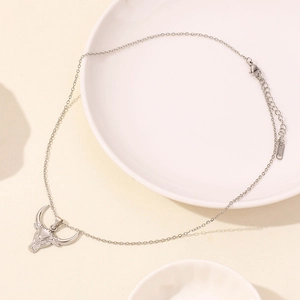 Macro shot of silver bull head pendant with O-chain necklace on a ceramic plate