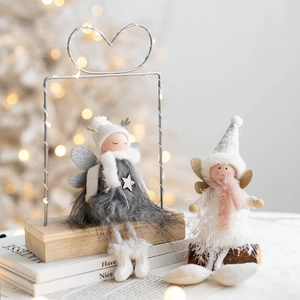 Christmas plush angel dolls in white and grey colors on a warm festive holiday background