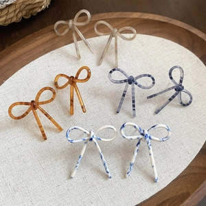 Vue détaillée des boucles d'oreilles nœuds en acétate aux motifs écaillés et marbrés