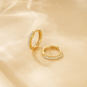 Detailed macro view of S925 sterling silver stamp on golden crystal huggie hoop earrings