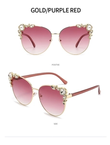 Detailed close-up of gold cat-eye sunglasses with purple red lenses and rhinestone accents