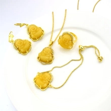 Macro shot of gold-plated Buddha pendant jewelry set with yellow jade and zircons