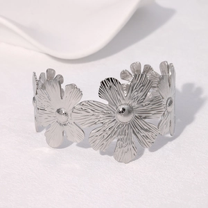 Detailed close-up of a silver daisy flower cuff bracelet in polished stainless steel