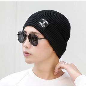 Detail of black ribbed knit beanie with embroidered text patch on professional male model