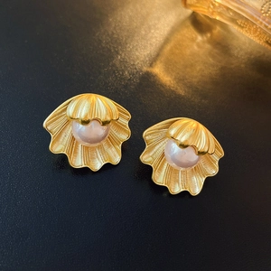 Macro shot of vintage shell-shaped matte gold stud earrings with iridescent pearls