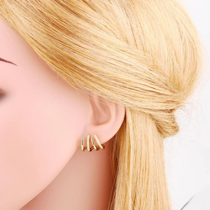 Eleganti orecchini a clip dorati a quattro griffe con micro cristalli su modella