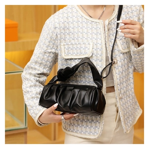 Detail of black pleated cloud bag featuring a unique knotted handle and soft leather texture