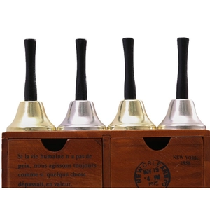 Golden and silver Christmas hand bells set with black handles on a vintage wooden box