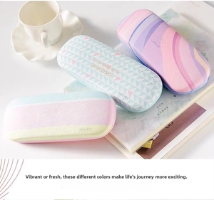Three patterned hard-shell eyeglasses cases with pastel geometric designs on a magazine