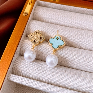 Detailed view of vintage gold clover earrings with zircons and hanging white pearl
