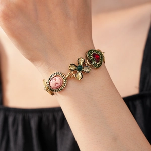 Détail d'un bracelet vintage doré avec camées roses et breloques en pierres colorées