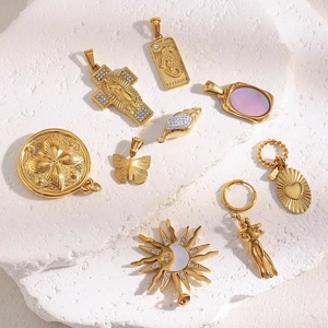 Macro detail of various 18K gold plated stainless steel pendants on a white stone texture