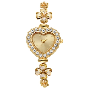 Macro shot of gold heart-shaped quartz watch with diamond bezel and clover chain band