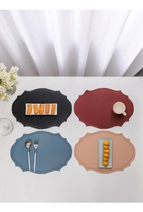 Set of four colorful oval leather placemats in grey red blue and beige on table