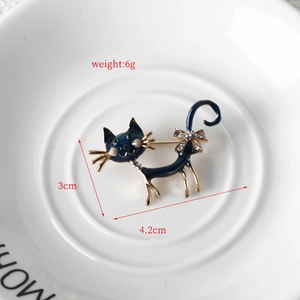 Detailed size view of a blue enamel cat brooch with gold trim and crystal bow detail