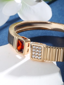 Detail of luxury gold bracelet with red rectangular gem and sparkling zircons