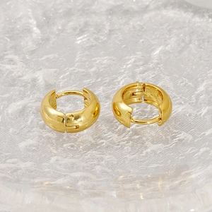 Macro shot of chunky gold hoop earrings with polished finish and spring hinge closure