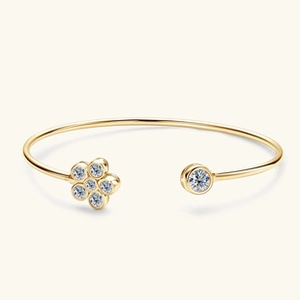 Dettaglio di bracciale rigido in moissanite dorata con fiore a sei petali e diamanti tondi