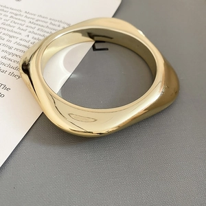 Gros plan d'un bracelet géométrique doré aux formes ondulées et finition brillante