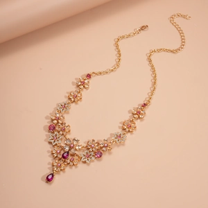 Macro detail of gold flower necklace with pink crystals and drop pendant