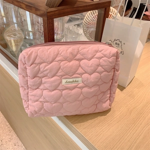 Detail of pink heart-quilted makeup bag showing soft puffy texture and zipper closure