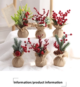 Mini artificial Christmas tree set with red berries and pine cones in burlap base