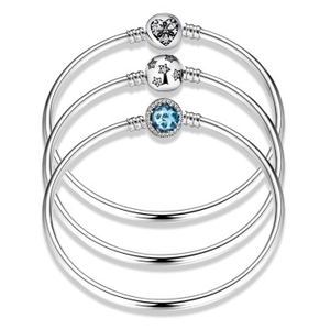 Close-up of S925 silver bangles featuring heart, star, and blue gemstone charms