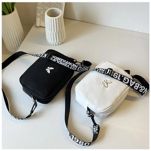 Detail of black and white nylon crossbody bags with butterfly charm and wide logo straps