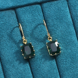Gros plan détaillé de boucles d'oreilles plaquées or 18K avec zircons verts émeraude