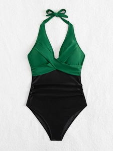 Detail of emerald green and black halter swimsuit with ruching and bow tie