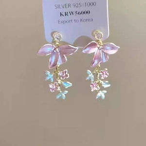 Détail de boucles d'oreilles fleurs en émail rose et bleu avec aiguilles en argent 925 et cristaux
