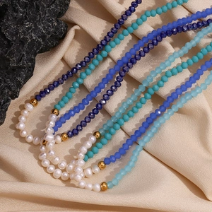 Detailed view of freshwater pearls and blue faceted crystals on beige silk fabric