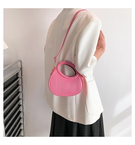 Pink semi-circle saddle bag with vertical stripe texture worn as a crossbody bag